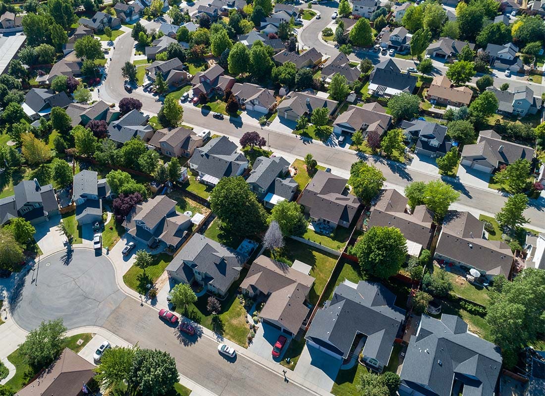 Aurelia, IA - Aerial View of a Quiet Suburban Neighborhood with Homes Surrounded by Green Trees on a Sunny Day